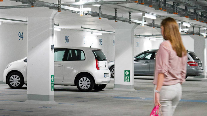Woman walks to car in well-lit underground car park 